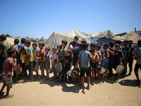 Displaced Palestinians are gathering to receive food cooked by a charity kitchen, amid food scarcity, as the Israel-Hamas conflict continues...