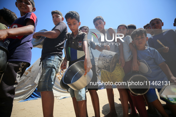 Displaced Palestinians are gathering to receive food cooked by a charity kitchen, amid food scarcity, as the Israel-Hamas conflict continues...