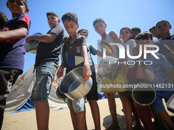 Displaced Palestinians are gathering to receive food cooked by a charity kitchen, amid food scarcity, as the Israel-Hamas conflict continues...