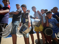 Displaced Palestinians are gathering to receive food cooked by a charity kitchen, amid food scarcity, as the Israel-Hamas conflict continues...