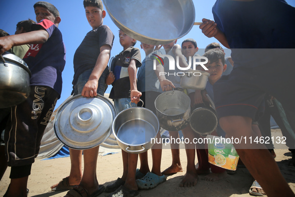 Displaced Palestinians are gathering to receive food cooked by a charity kitchen, amid food scarcity, as the Israel-Hamas conflict continues...