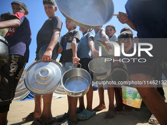 Displaced Palestinians are gathering to receive food cooked by a charity kitchen, amid food scarcity, as the Israel-Hamas conflict continues...