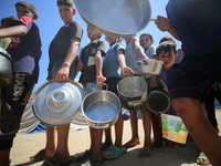 Displaced Palestinians are gathering to receive food cooked by a charity kitchen, amid food scarcity, as the Israel-Hamas conflict continues...