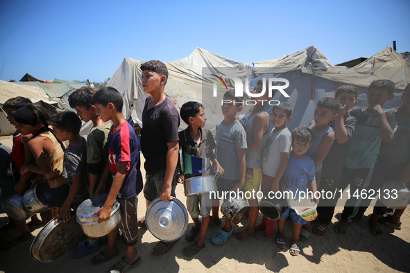 Displaced Palestinians are gathering to receive food cooked by a charity kitchen, amid food scarcity, as the Israel-Hamas conflict continues...