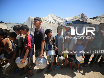 Displaced Palestinians are gathering to receive food cooked by a charity kitchen, amid food scarcity, as the Israel-Hamas conflict continues...