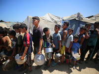 Displaced Palestinians are gathering to receive food cooked by a charity kitchen, amid food scarcity, as the Israel-Hamas conflict continues...