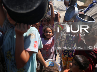 Displaced Palestinians are gathering to receive food cooked by a charity kitchen, amid food scarcity, as the Israel-Hamas conflict continues...