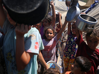 Displaced Palestinians are gathering to receive food cooked by a charity kitchen, amid food scarcity, as the Israel-Hamas conflict continues...