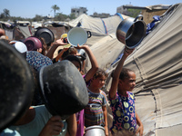 Displaced Palestinians are gathering to receive food cooked by a charity kitchen, amid food scarcity, as the Israel-Hamas conflict continues...