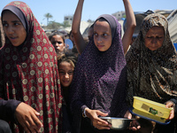 Displaced Palestinians are gathering to receive food cooked by a charity kitchen, amid food scarcity, as the Israel-Hamas conflict continues...