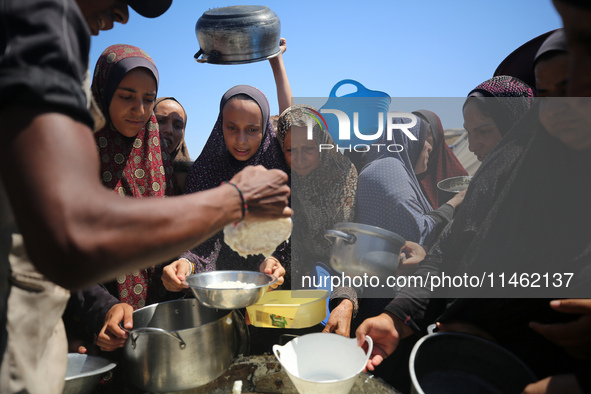 Displaced Palestinians are gathering to receive food cooked by a charity kitchen, amid food scarcity, as the Israel-Hamas conflict continues...