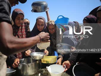 Displaced Palestinians are gathering to receive food cooked by a charity kitchen, amid food scarcity, as the Israel-Hamas conflict continues...