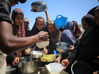 Displaced Palestinians are gathering to receive food cooked by a charity kitchen, amid food scarcity, as the Israel-Hamas conflict continues...