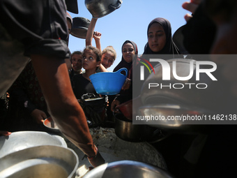 Displaced Palestinians are gathering to receive food cooked by a charity kitchen, amid food scarcity, as the Israel-Hamas conflict continues...