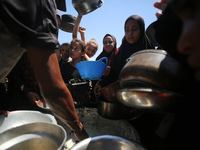 Displaced Palestinians are gathering to receive food cooked by a charity kitchen, amid food scarcity, as the Israel-Hamas conflict continues...