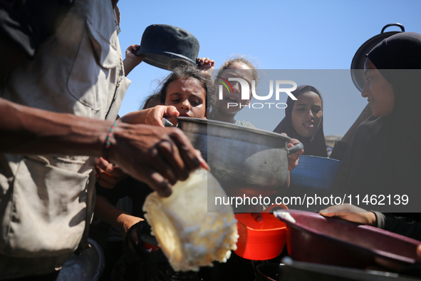 Displaced Palestinians are gathering to receive food cooked by a charity kitchen, amid food scarcity, as the Israel-Hamas conflict continues...