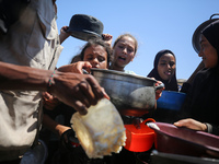 Displaced Palestinians are gathering to receive food cooked by a charity kitchen, amid food scarcity, as the Israel-Hamas conflict continues...