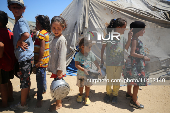 Displaced Palestinians are gathering to receive food cooked by a charity kitchen, amid food scarcity, as the Israel-Hamas conflict continues...