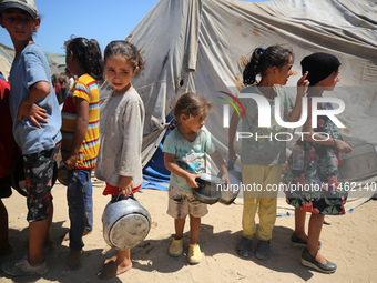 Displaced Palestinians are gathering to receive food cooked by a charity kitchen, amid food scarcity, as the Israel-Hamas conflict continues...