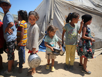 Displaced Palestinians are gathering to receive food cooked by a charity kitchen, amid food scarcity, as the Israel-Hamas conflict continues...