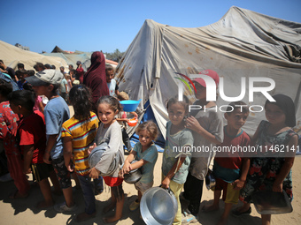 Displaced Palestinians are gathering to receive food cooked by a charity kitchen, amid food scarcity, as the Israel-Hamas conflict continues...