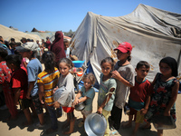 Displaced Palestinians are gathering to receive food cooked by a charity kitchen, amid food scarcity, as the Israel-Hamas conflict continues...