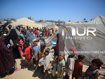 Displaced Palestinians are gathering to receive food cooked by a charity kitchen, amid food scarcity, as the Israel-Hamas conflict continues...