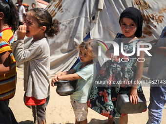 Displaced Palestinians are gathering to receive food cooked by a charity kitchen, amid food scarcity, as the Israel-Hamas conflict continues...