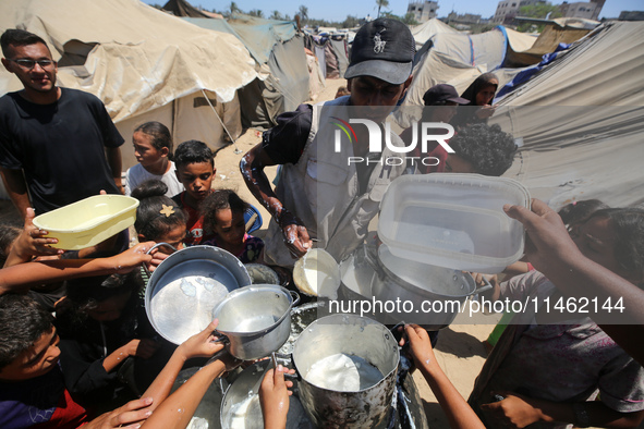 Displaced Palestinians are gathering to receive food cooked by a charity kitchen, amid food scarcity, as the Israel-Hamas conflict continues...