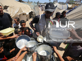 Displaced Palestinians are gathering to receive food cooked by a charity kitchen, amid food scarcity, as the Israel-Hamas conflict continues...