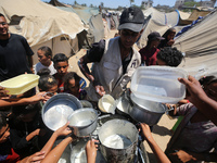 Displaced Palestinians are gathering to receive food cooked by a charity kitchen, amid food scarcity, as the Israel-Hamas conflict continues...