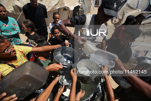 Displaced Palestinians are gathering to receive food cooked by a charity kitchen, amid food scarcity, as the Israel-Hamas conflict continues...