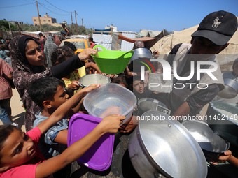 Displaced Palestinians are gathering to receive food cooked by a charity kitchen, amid food scarcity, as the Israel-Hamas conflict continues...