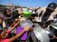 Displaced Palestinians are gathering to receive food cooked by a charity kitchen, amid food scarcity, as the Israel-Hamas conflict continues...