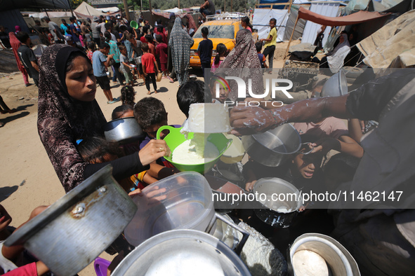 Displaced Palestinians are gathering to receive food cooked by a charity kitchen, amid food scarcity, as the Israel-Hamas conflict continues...