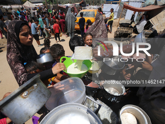 Displaced Palestinians are gathering to receive food cooked by a charity kitchen, amid food scarcity, as the Israel-Hamas conflict continues...