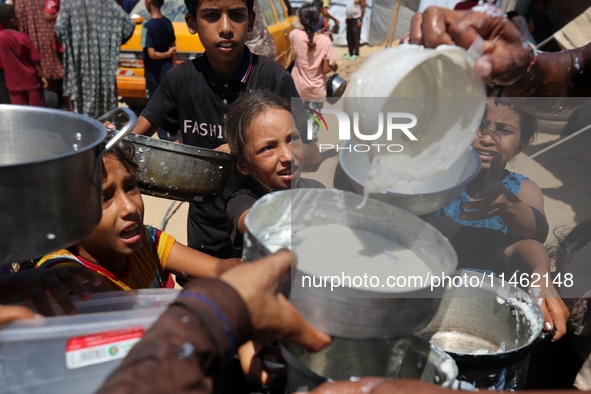 Displaced Palestinians are gathering to receive food cooked by a charity kitchen, amid food scarcity, as the Israel-Hamas conflict continues...