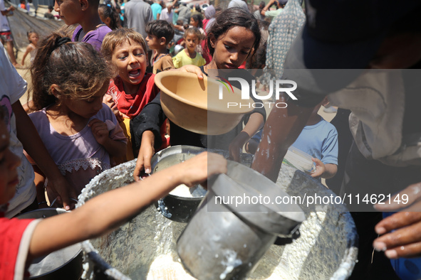 Displaced Palestinians are gathering to receive food cooked by a charity kitchen, amid food scarcity, as the Israel-Hamas conflict continues...