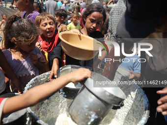 Displaced Palestinians are gathering to receive food cooked by a charity kitchen, amid food scarcity, as the Israel-Hamas conflict continues...