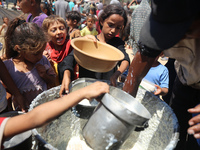 Displaced Palestinians are gathering to receive food cooked by a charity kitchen, amid food scarcity, as the Israel-Hamas conflict continues...