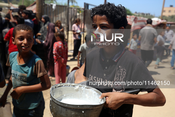 A Palestinian is carrying food cooked by a charity kitchen, amid shortages of aid supplies, as the conflict between Israel and Hamas continu...