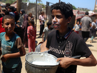 A Palestinian is carrying food cooked by a charity kitchen, amid shortages of aid supplies, as the conflict between Israel and Hamas continu...