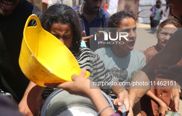 Displaced Palestinians are gathering to receive food cooked by a charity kitchen, amid food scarcity, as the Israel-Hamas conflict continues...