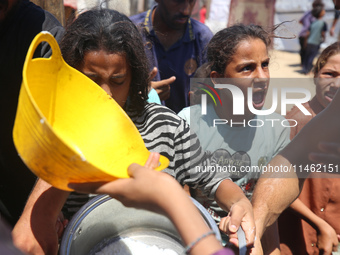 Displaced Palestinians are gathering to receive food cooked by a charity kitchen, amid food scarcity, as the Israel-Hamas conflict continues...