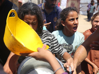 Displaced Palestinians are gathering to receive food cooked by a charity kitchen, amid food scarcity, as the Israel-Hamas conflict continues...