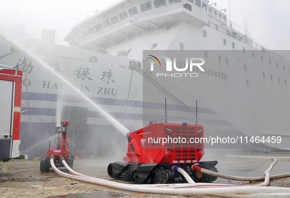 A fire-fighting robot is performing fire-fighting operations during a comprehensive defense mobilization drill in Yantai, China, on August 9...