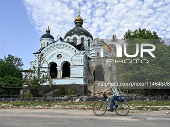 A man is riding a bicycle past the Church of the Nativity of the Blessed Virgin Mary, which was damaged by Russian shelling on July 8, in No...