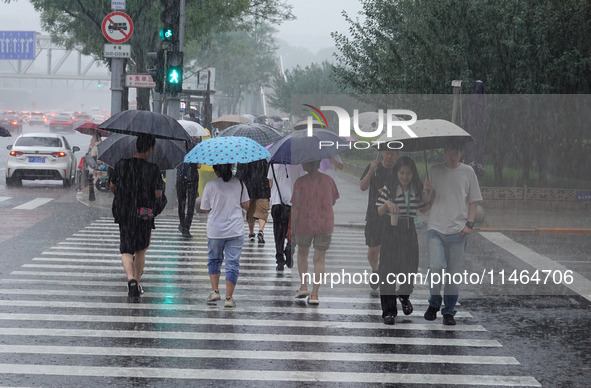 Pedestrians are walking during a rainstorm in Beijing, China, on August 9, 2024. 