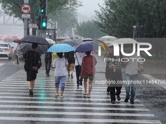 Pedestrians are walking during a rainstorm in Beijing, China, on August 9, 2024. (