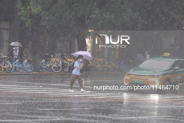 Pedestrians are walking during a rainstorm in Beijing, China, on August 9, 2024. 